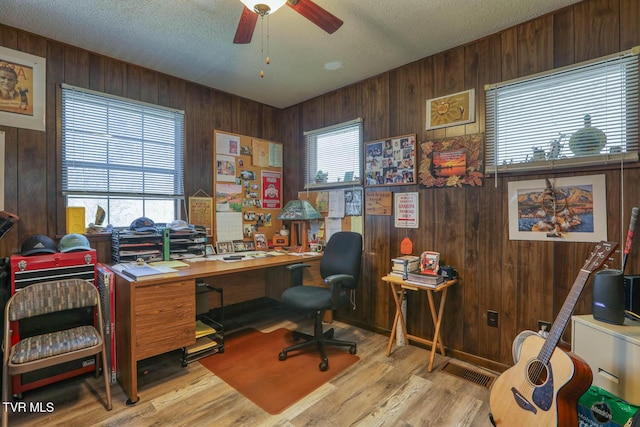 office featuring a wealth of natural light, wood finished floors, wood walls, and ceiling fan