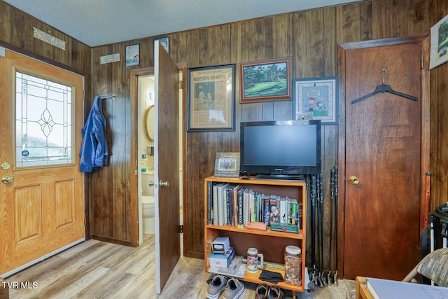 entrance foyer featuring wooden walls, wood finished floors, and a textured ceiling