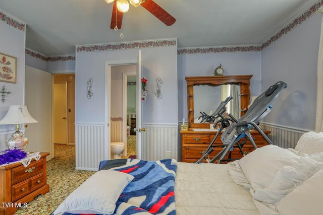 carpeted bedroom featuring a wainscoted wall and ceiling fan