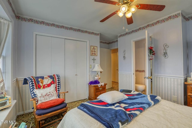 bedroom with a closet, a ceiling fan, and wainscoting