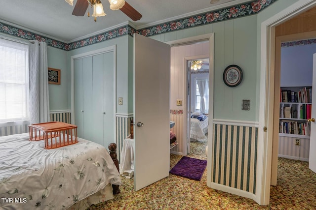 bedroom featuring ornamental molding, carpet flooring, a closet, a textured ceiling, and a ceiling fan