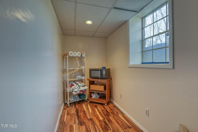 interior space featuring recessed lighting, a drop ceiling, baseboards, and wood finished floors