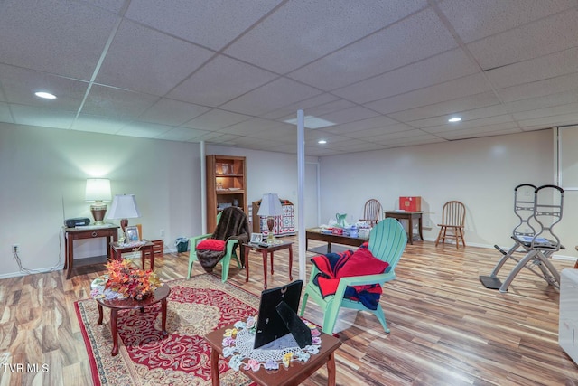 living room featuring wood finished floors, baseboards, and a drop ceiling