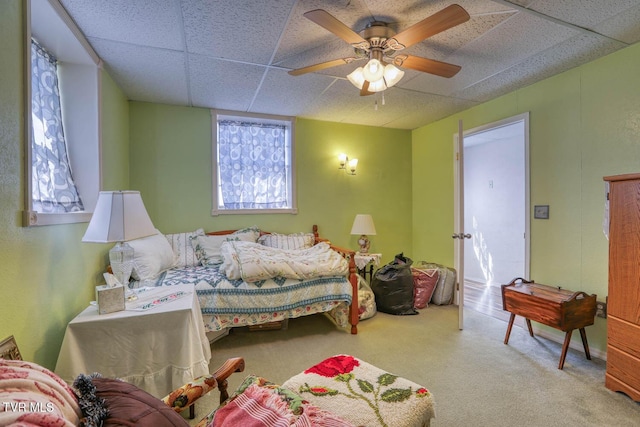 bedroom with a drop ceiling, carpet floors, and ceiling fan