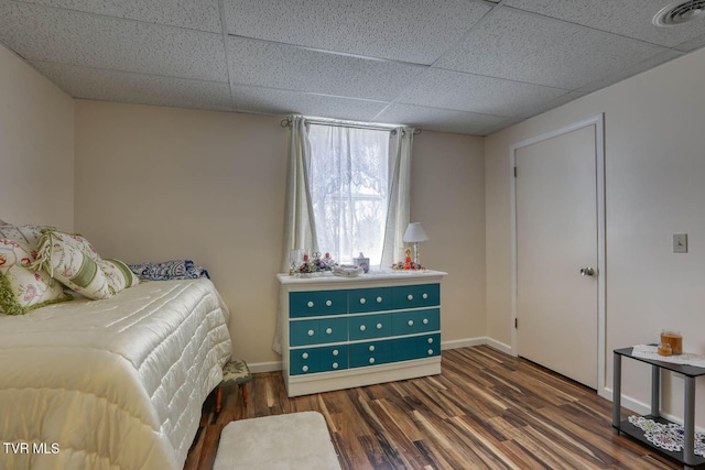 bedroom featuring visible vents, a paneled ceiling, baseboards, and wood finished floors