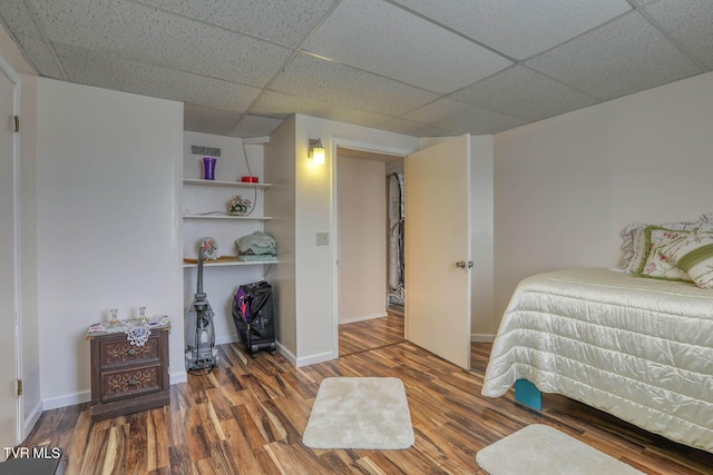 bedroom with a paneled ceiling, baseboards, and wood finished floors