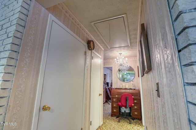 hallway featuring a textured ceiling and attic access