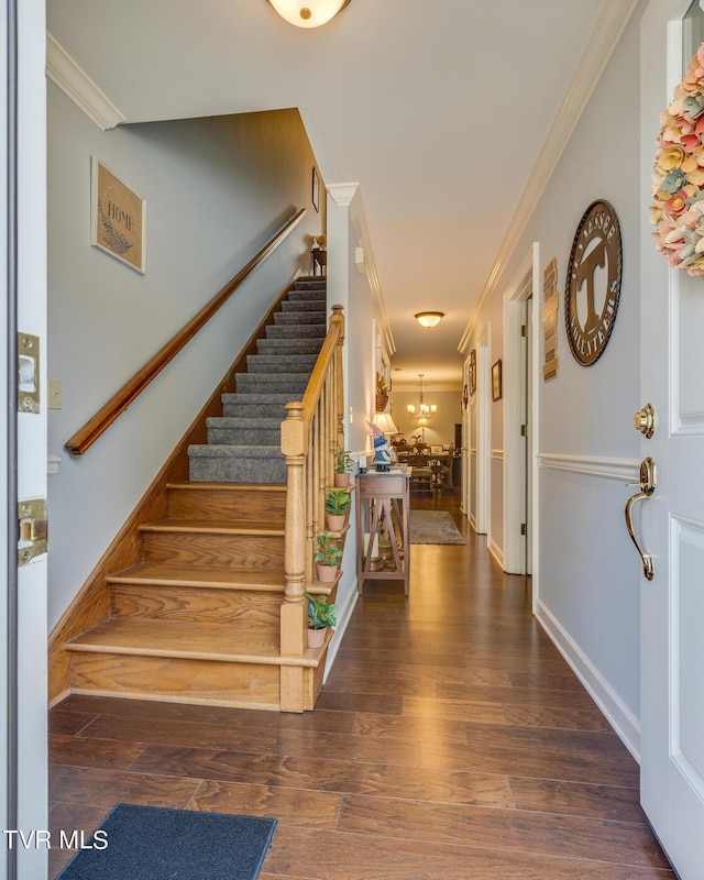 foyer with a chandelier, wood finished floors, crown molding, and stairway