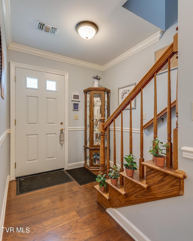 entryway with visible vents, crown molding, baseboards, stairway, and wood finished floors