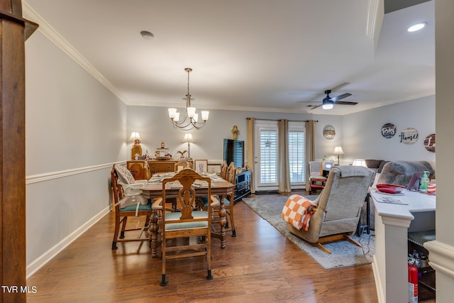 dining area with baseboards, wood finished floors, crown molding, and ceiling fan with notable chandelier