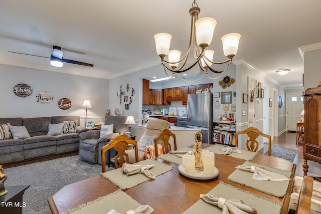 dining area featuring ceiling fan with notable chandelier, crown molding, and wood finished floors