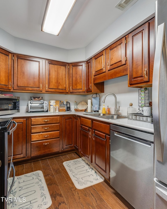 kitchen with a sink, light countertops, dark wood-style floors, and stainless steel appliances