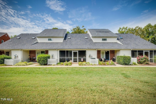 view of front of home with a front yard, brick siding, and a sunroom