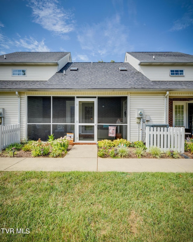 back of house featuring fence, a lawn, a sunroom, and a shingled roof