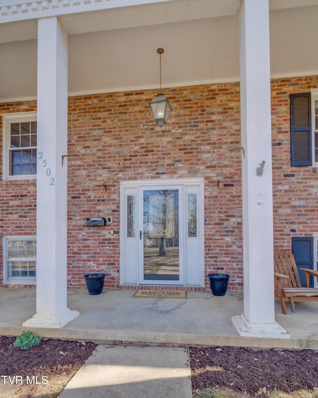 property entrance featuring brick siding and covered porch