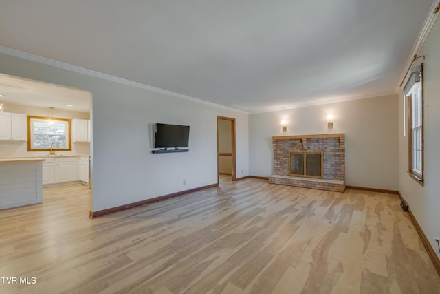 unfurnished living room featuring a sink, light wood-type flooring, a fireplace, and crown molding