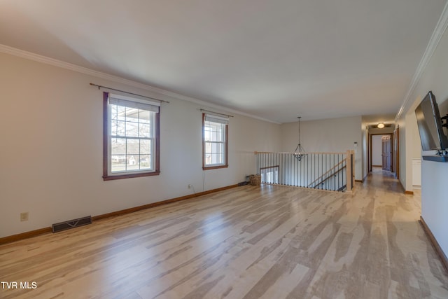 spare room with crown molding, light wood-style floors, visible vents, and baseboards