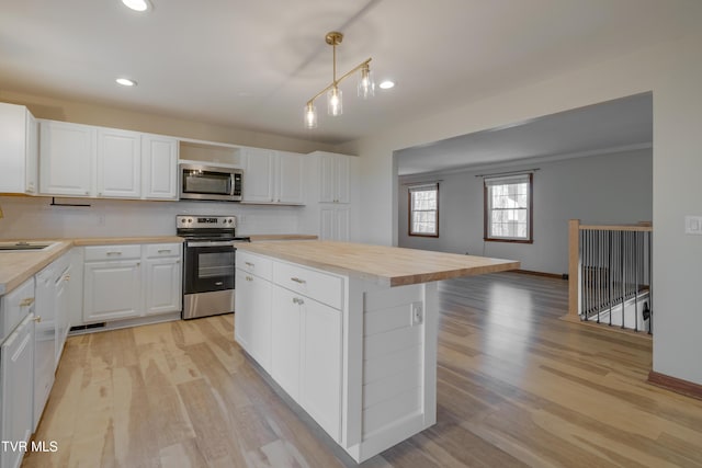 kitchen featuring tasteful backsplash, wooden counters, light wood-style flooring, appliances with stainless steel finishes, and white cabinets