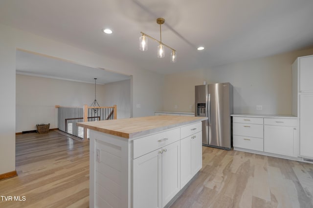 kitchen with white cabinetry, light wood-style floors, stainless steel fridge, and pendant lighting