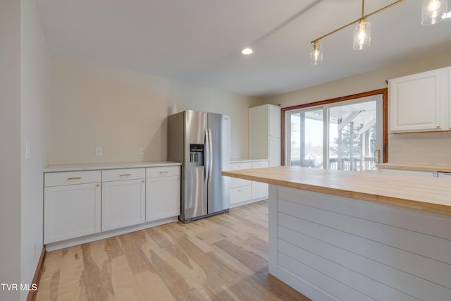 kitchen featuring pendant lighting, butcher block countertops, light wood-style flooring, white cabinetry, and stainless steel fridge with ice dispenser