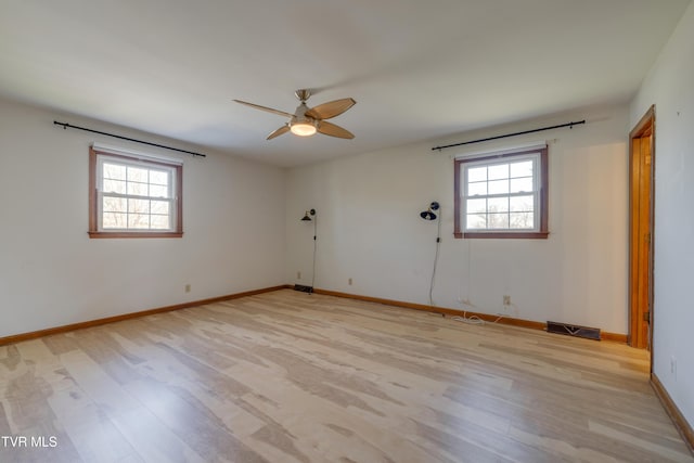 empty room featuring a wealth of natural light, light wood finished floors, and baseboards