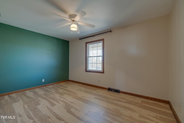 unfurnished room featuring light wood-style flooring, baseboards, visible vents, and ceiling fan