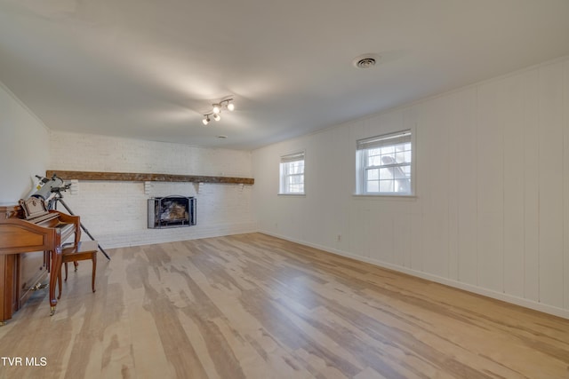 living room with visible vents, ornamental molding, wood finished floors, brick wall, and a fireplace