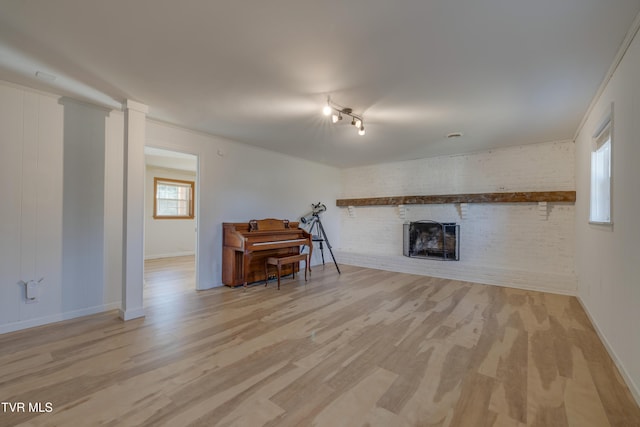 unfurnished living room featuring a brick fireplace, brick wall, baseboards, and wood finished floors