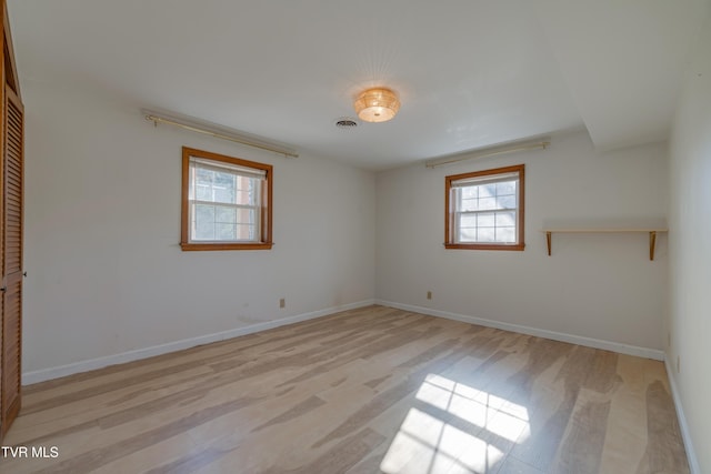 empty room with visible vents, light wood-style flooring, and baseboards