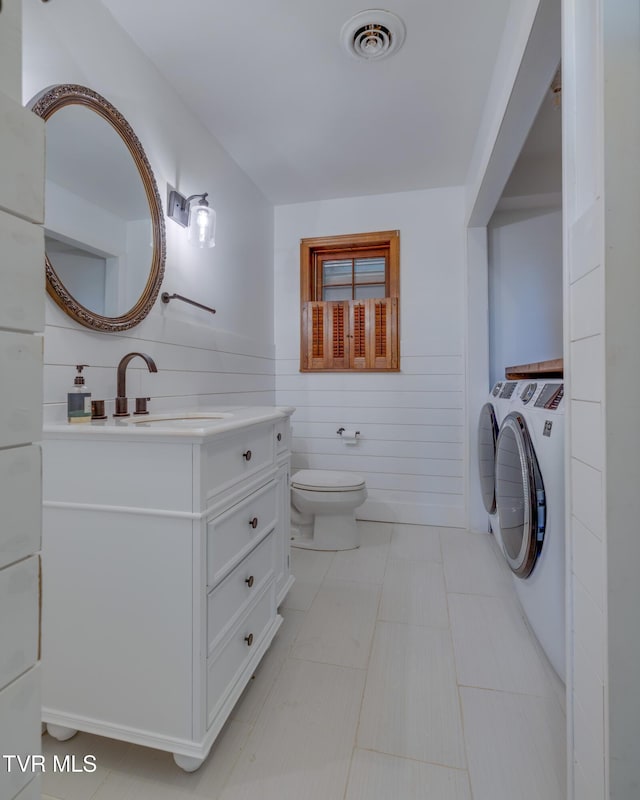 bathroom with visible vents, washer and clothes dryer, toilet, tile patterned floors, and vanity