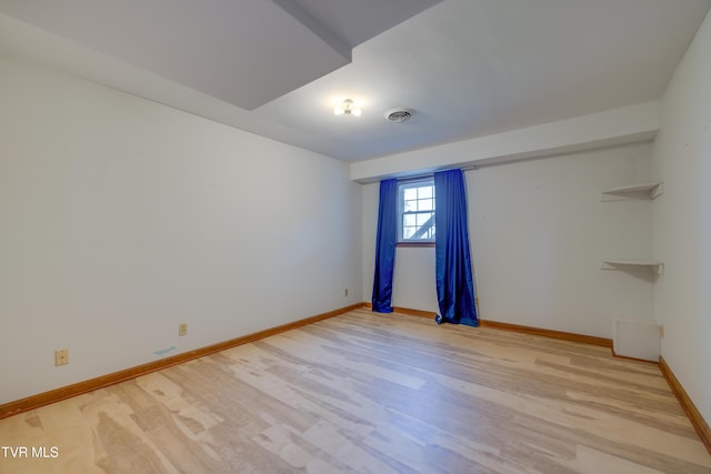 spare room with visible vents, baseboards, and wood finished floors