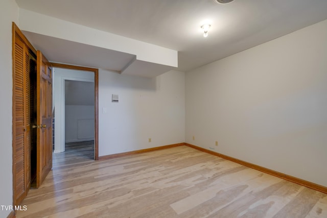 spare room with baseboards and light wood finished floors