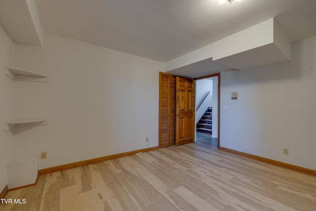 spare room with baseboards, light wood-style flooring, and stairs