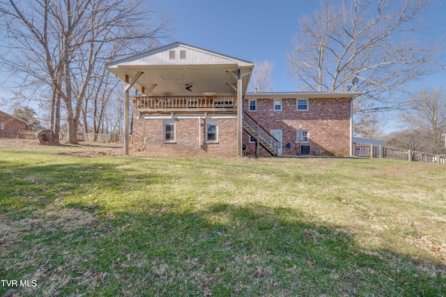 back of property with stairway, a yard, a ceiling fan, and brick siding