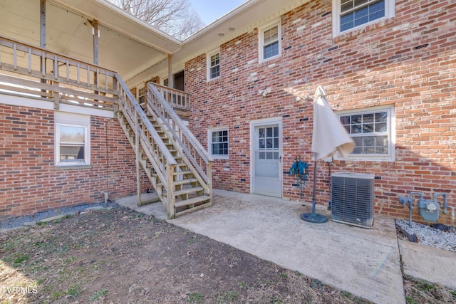 exterior space with stairs, brick siding, and central AC