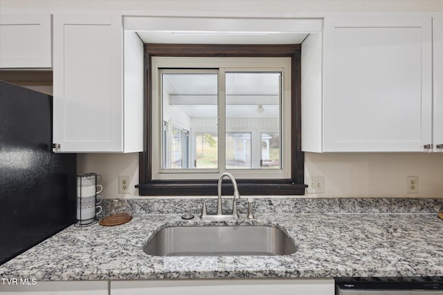 kitchen featuring a sink, light stone countertops, dishwasher, and white cabinetry