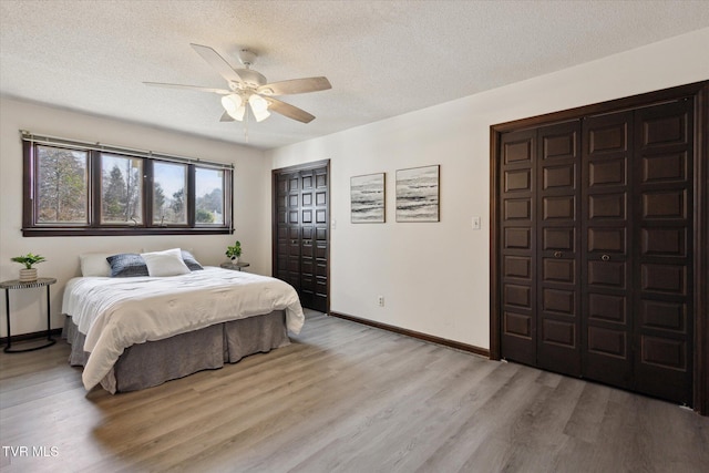 bedroom featuring light wood finished floors, a textured ceiling, baseboards, and a ceiling fan