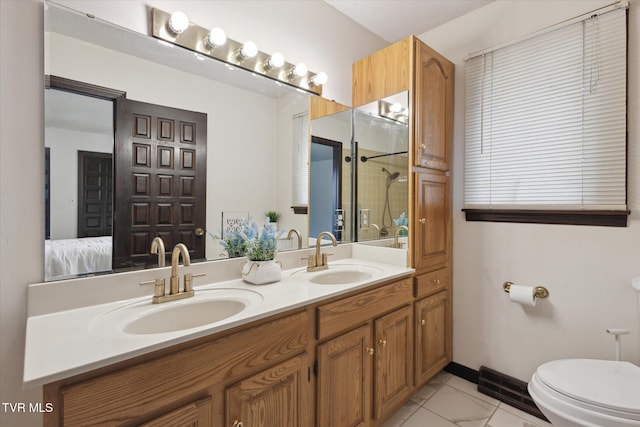 ensuite bathroom with a sink, toilet, walk in shower, and double vanity