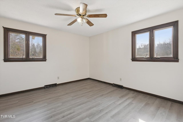 empty room with a ceiling fan, baseboards, visible vents, and light wood-type flooring