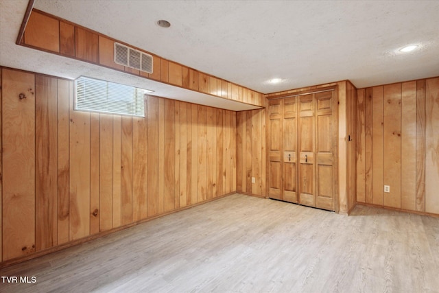 below grade area with visible vents, baseboards, wooden walls, and wood finished floors