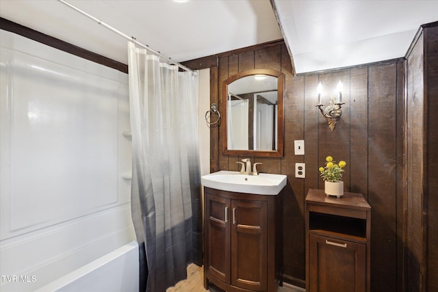 full bath featuring wood walls, vanity, and shower / bath combination with curtain