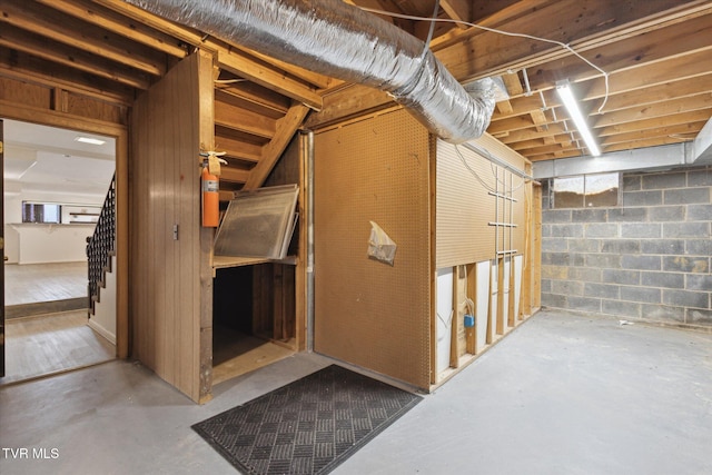 unfinished basement with stairway and concrete block wall