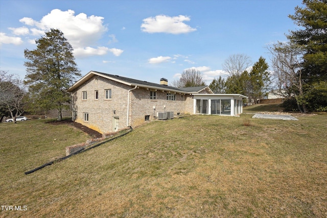 rear view of house featuring a yard, brick siding, a sunroom, and a chimney