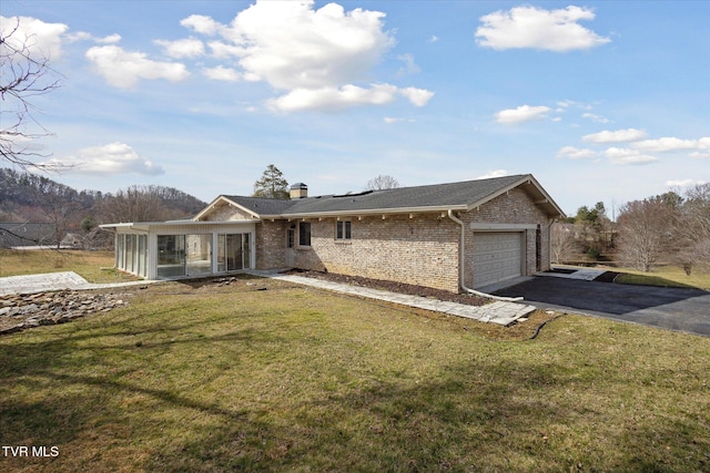 single story home with a front lawn, driveway, an attached garage, a sunroom, and brick siding