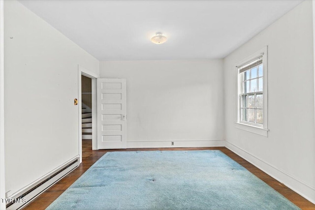 spare room with stairs, dark wood-type flooring, baseboards, and a baseboard radiator