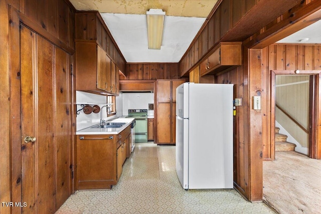 kitchen with freestanding refrigerator, a sink, range with electric cooktop, light countertops, and wood walls