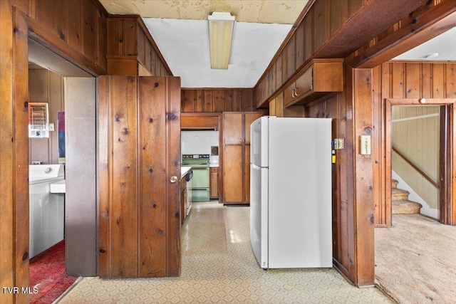 kitchen with white appliances, wooden walls, and light floors