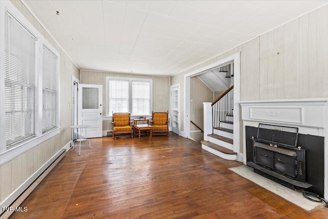 unfurnished room with stairs, a baseboard heating unit, and wood-type flooring