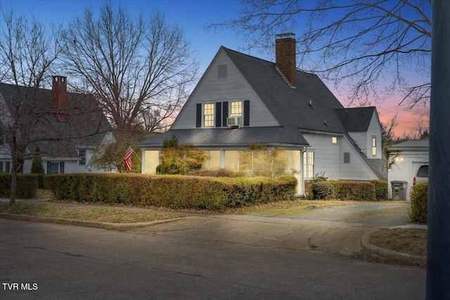 view of front facade with cooling unit, a chimney, and a shingled roof