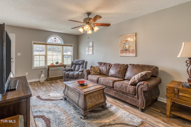 living room with a ceiling fan, wood finished floors, baseboards, and a textured ceiling